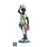 A late 19th to early 20th Century majolica figure of an African boy holding a basket in one hand and