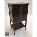 An Edwardian mahogany five drawer music cabinet on slender legs united by an under-tier, lacking