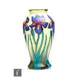 A Moorcroft Enamels vase decorated with hand painted purple flag iris against a pale yellow