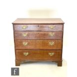 A George III crossbanded mahogany oak chest of four long drawers, brass fret drop handles, on
