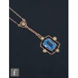 An early 20th Century 9ct blue topaz and seed pearl pendant, central rectangular cut topaz with four
