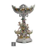 A 20th Century Dresden type table centre, the pedestal with three cherub figures amidst encrusted