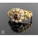 A 15ct almandine garnet and split pearl ring, central garnet within pearl border to pierced shoulder