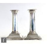 A pair of hallmarked silver piano candlesticks, square stepped bases with beaded borders below