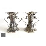 A pair of hallmarked silver Art Nouveau small twin handled vases, each decorated with stylised