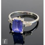 A 14ct white gold tanzanite and diamond three stone ring, emerald cut tanzanite flanked by