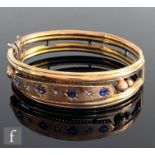 An early 20th Century 9ct hallmarked sapphire and diamond set tubular hinged bangle with seven gypsy