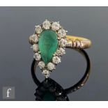 An emerald and diamond cluster ring, central pear shaped emerald, length 9mm, within a thirteen