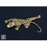 A modern 14ct brooch modelled as a crawling leopard with black enamel spots, emerald set eyes and