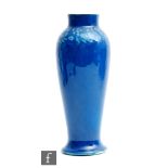 Ruskin Pottery - A souffle glaze vase of slender barrel form with a collar neck and splayed foot,