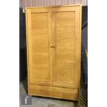 Ercol Furniture - A light oak Bosco range wardrobe, fitted with double doors above a drawer to the