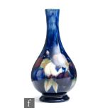 William Moorcroft - A bud vase of footed form decorated in the Wisteria pattern, impressed mark