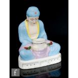 In the manner of Limoges - A 1930s Art Deco inkwell modelled as a seated Buddha holding a vessel,