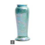 Ruskin Pottery - A vase of slender form with a splayed foot decorated in an all over mottled green