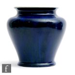 Ruskin Pottery - A souffle glazed vase of compressed form decorated in a streaked blue glaze with