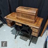 An early 20th Century treadle sewing machine by Pashells in an inlaid banded drawer stand, width