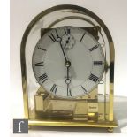 A contemporary Kieninger mantel clock of arched form in a polished brass and acrylic case, the