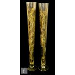 A pair of clear glass floor vases with a tapered cylindrical body to a circular spread foot,
