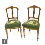 A set of four Victorian carved walnut drawing room chairs on fluted legs terminating in peg feet,