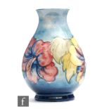 A Moorcroft footed baluster form vase decorated in the Hibiscus pattern against a blue wash