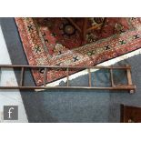 A 19th Century pitch pine nine rung library pole ladder, with metamorphic collapsing action,