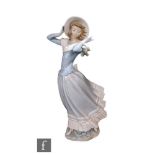 A large Lladro model of a lady stood holding her bonnet in the wind, printed mark, height 36.5cm.