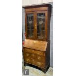 A George III style oak bureau bookcase enclosed by a pair of coloured leaded light doors over a