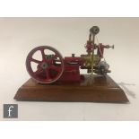 A Stuart single cylinder horizontal engine, painted red with six spoked flywheel, raised to a