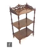 A Victorian mahogany three tier serpentine edge whatnot, turned supports below a pierced gallery,