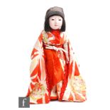 A Japanese gofun Ichimatsu doll, with dark inset eyes, dark wig and kimono, height 42cm, S/D.