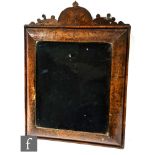 A late 18th to early 19th century small cushion shaped figured walnut wall mirror, surmounted with a