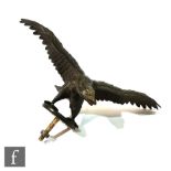 An early 20th Century bronze eagle with outstretched wings on a circular base, later drilled with