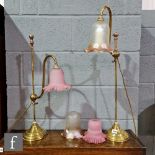A pair of Edwardian scroll arm brass table lamps, each with an amber and pink crimped edge shade,