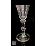 An 18th Century balustroid drinking glass circa 1740, the round funnel bowl above a flattened