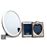 A hallmarked silver oval easel photograph frame of plain form, height 24cm, with two further smaller