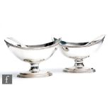 A pair of George III hallmarked silver pedestal boat shaped open salts, oval stepped base below