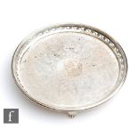 A hallmarked silver circular card waiter with central foliate engraved decoration within pierced