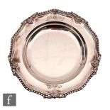 A George IV hallmarked silver shallow plate of plain form with engraved crest within gadroon and