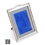A hallmarked silver rectangular easel photograph frame of plain form with foliate scroll