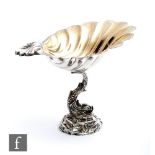 A hallmarked silver pedestal bon bon dish with a rocky base supporting a scrolling dolphin below a