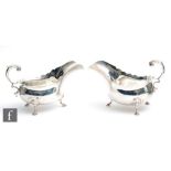 A pair of hallmarked silver sauce boats each raised on three stepped pad feet below plain bodies,