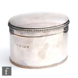 A modern hallmarked silver oval tea caddy of plain form with gadroon borders to foot rim and