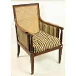 A late 19th Century bergére inlaid mahogany Armchair, with cane seat and back and a loose cushion on
