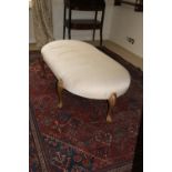 A large oval late 19th Century upholstered Centre Stool, covered in ivory fabric and raised on six