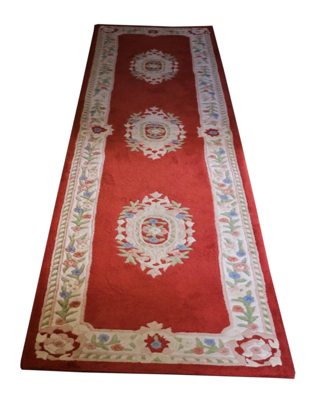 A set of three red/pink ground woollen Runners, each with a cream ground floral border and three