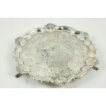 A silver Salver, London, with scrolling rim interspersed by shells, embossed centre on three hoof