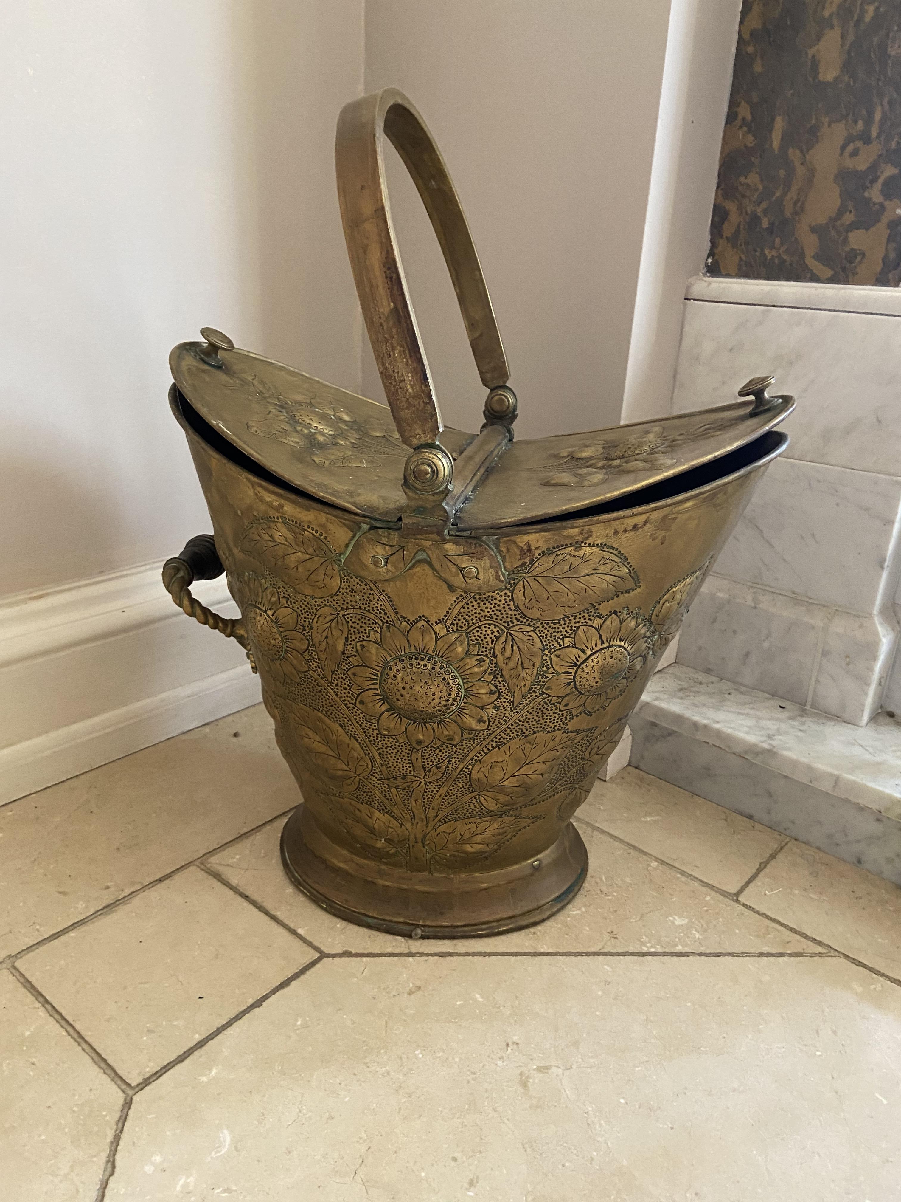 An embossed brass Coal Bucket, of helmet form with double hinged top with arched handle, 21'' (