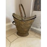 An embossed brass Coal Bucket, of helmet form with double hinged top with arched handle, 21'' (