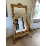 A rococo style gilt Cheval Dressing Mirror, with cartouche crest and scroll moulded frame, on a