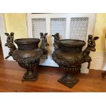 A pair of attractive heavy bronze two handled Urns, decorated with winged cherubs, trestle design